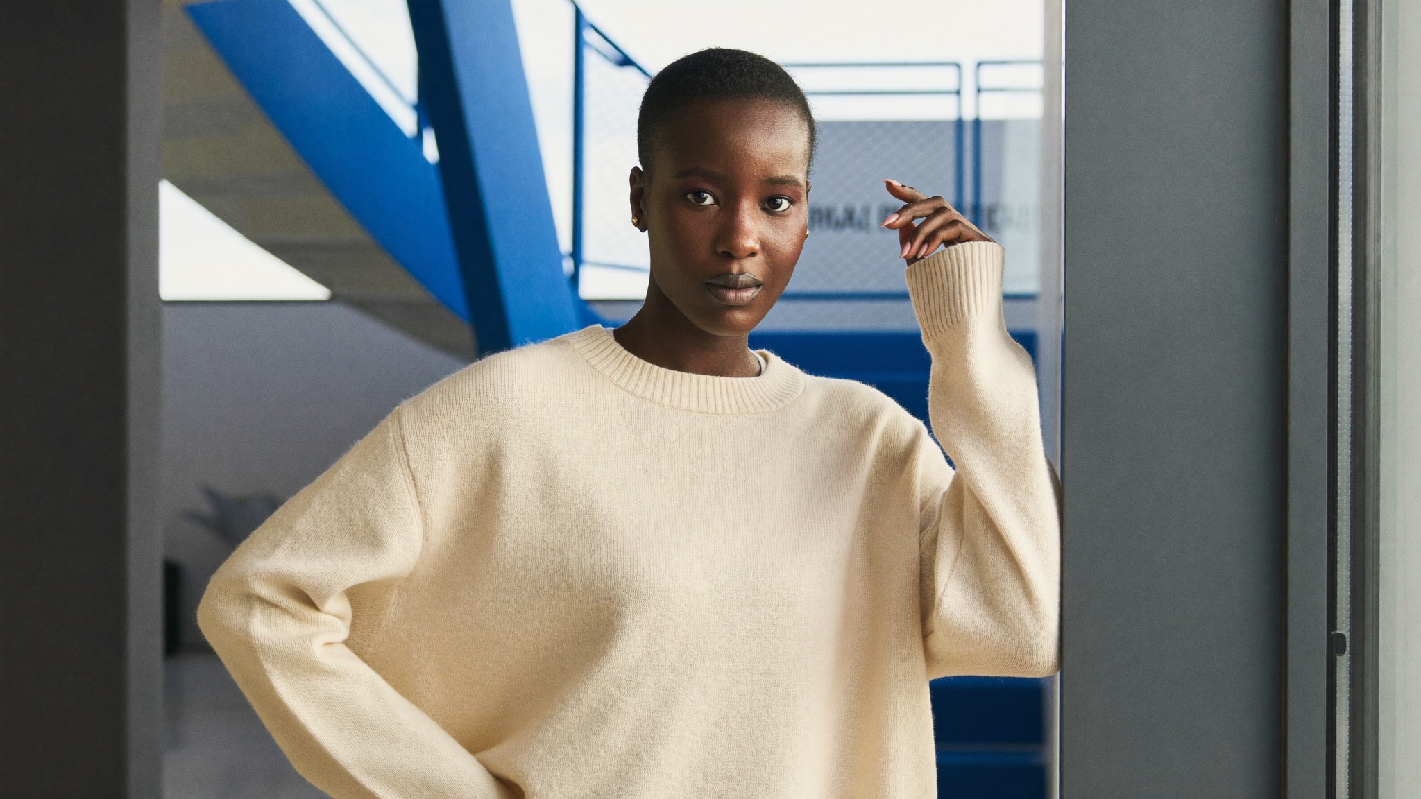 A poised, confident post-pregnancy woman at ease by a window in a modern interior